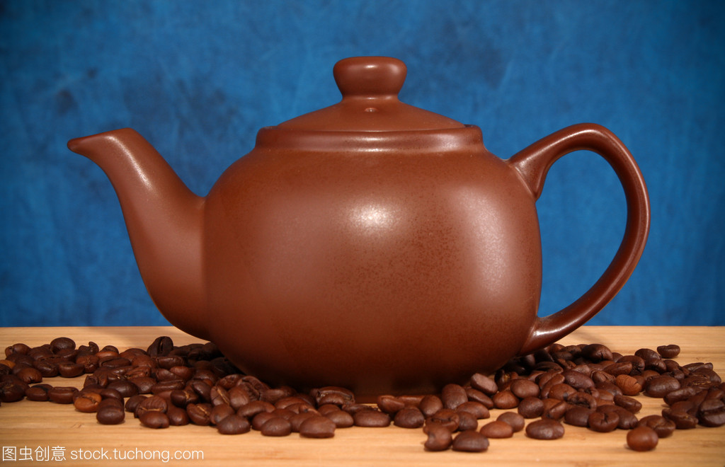 咖啡谷物在蓝色背景上的茶壶